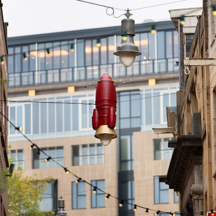 Street art featuring a red rocket-shaped light fixture creatively transforming public space lighting.