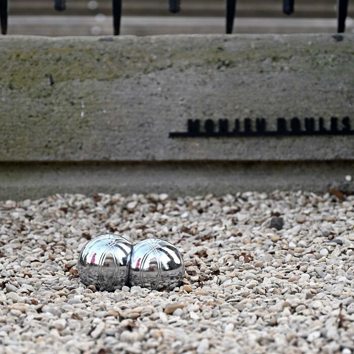 Two shiny metal balls on pebbles representing clever street art interpretations in a public space by Frankey.