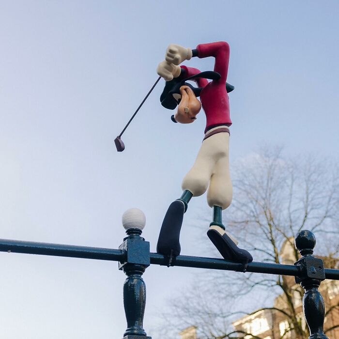 Street art interpretation of a cartoon character golfing creatively integrated into a public space railing.