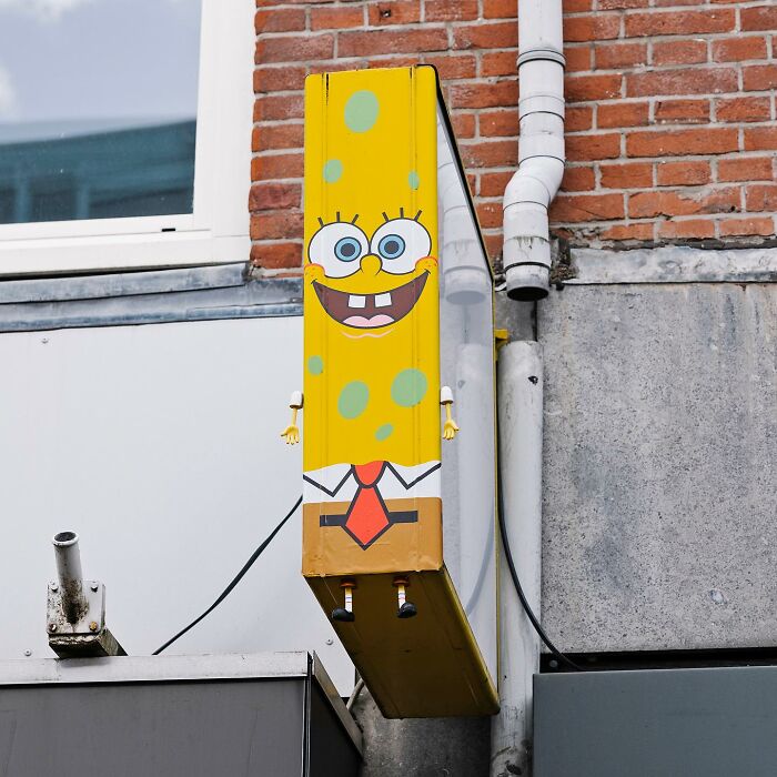 Street art on a public space creatively transforming a building fixture into a SpongeBob character illustration.
