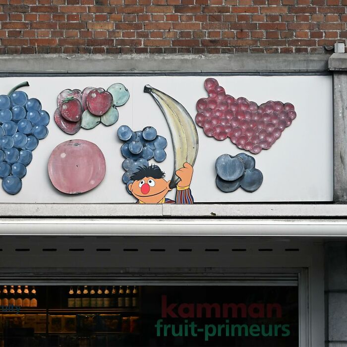 Street art of a character holding a banana surrounded by painted fruit on a public space wall by Frankey.