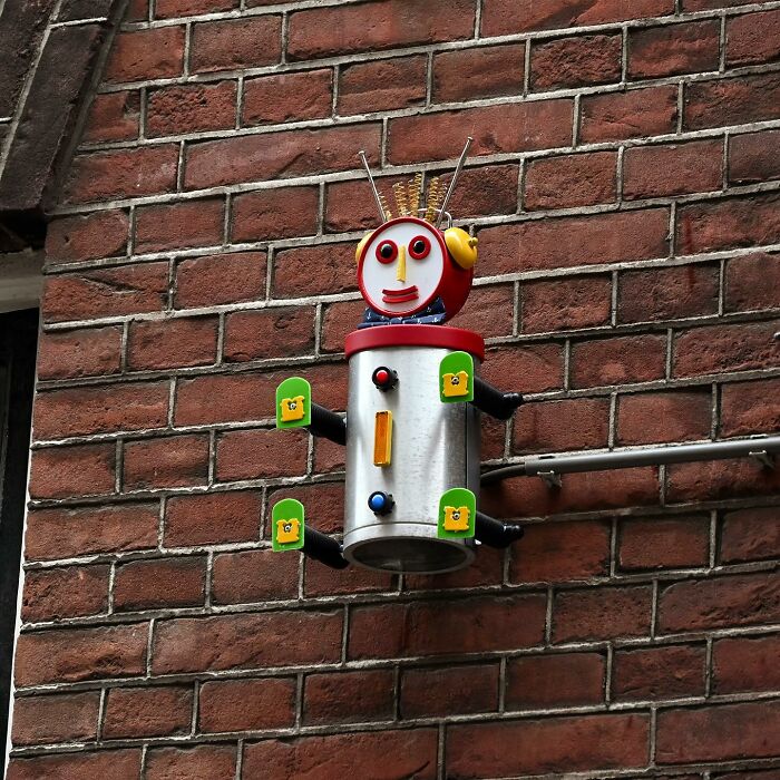 Street art robot sculpture attached to a brick wall, showcasing clever interpretations of public spaces by Frankey.