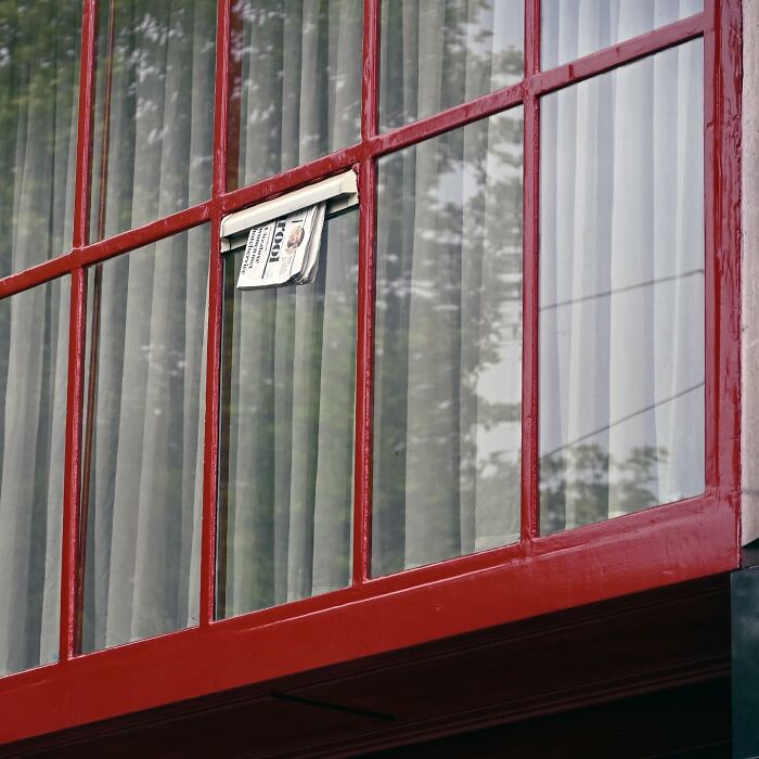 New and clever street art interpretation showing a window with red frames and a folded newspaper in public space.