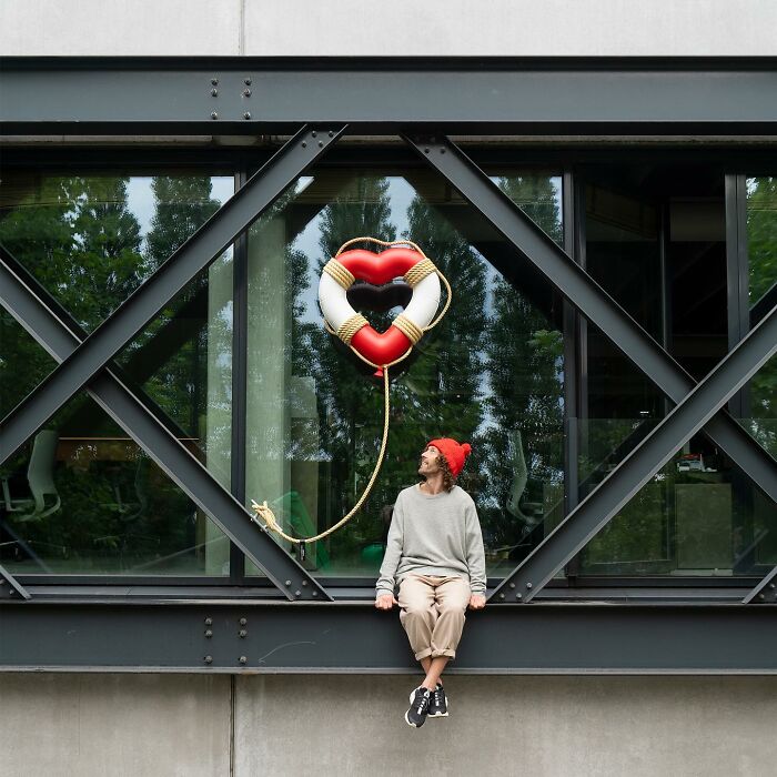 Man in red hat sitting near street art heart-shaped lifebuoy balloon on public space structure by Frankey.
