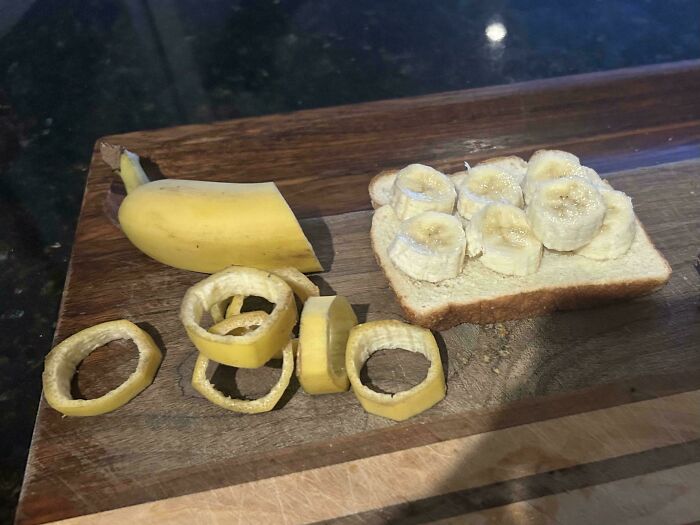 Banana peeled into rings next to sliced bananas on a piece of bread on a wooden cutting board, a quirky dish idea.