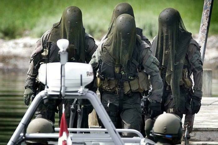 Military personnel wearing strange mesh face coverings in unsettling tactical setup