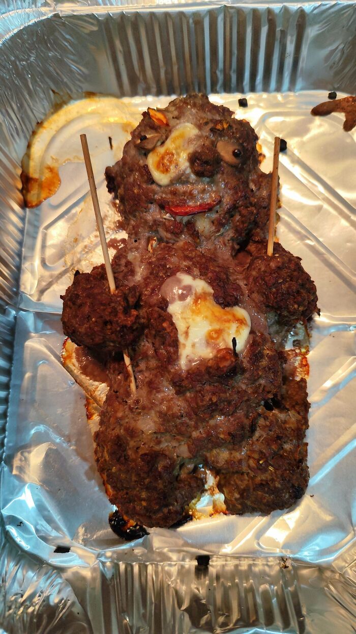 Meatloaf shaped like a bear with melted cheese in baking tray
