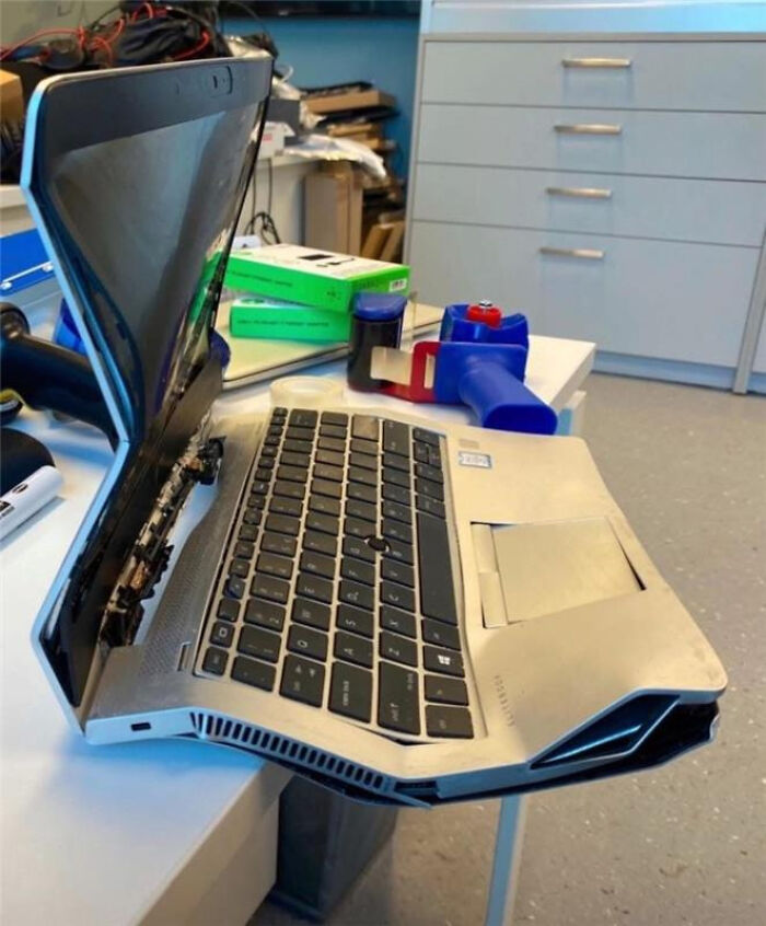 Bent and damaged laptop with broken screen and keyboard on a desk, illustrating tech support workers' challenging moments.