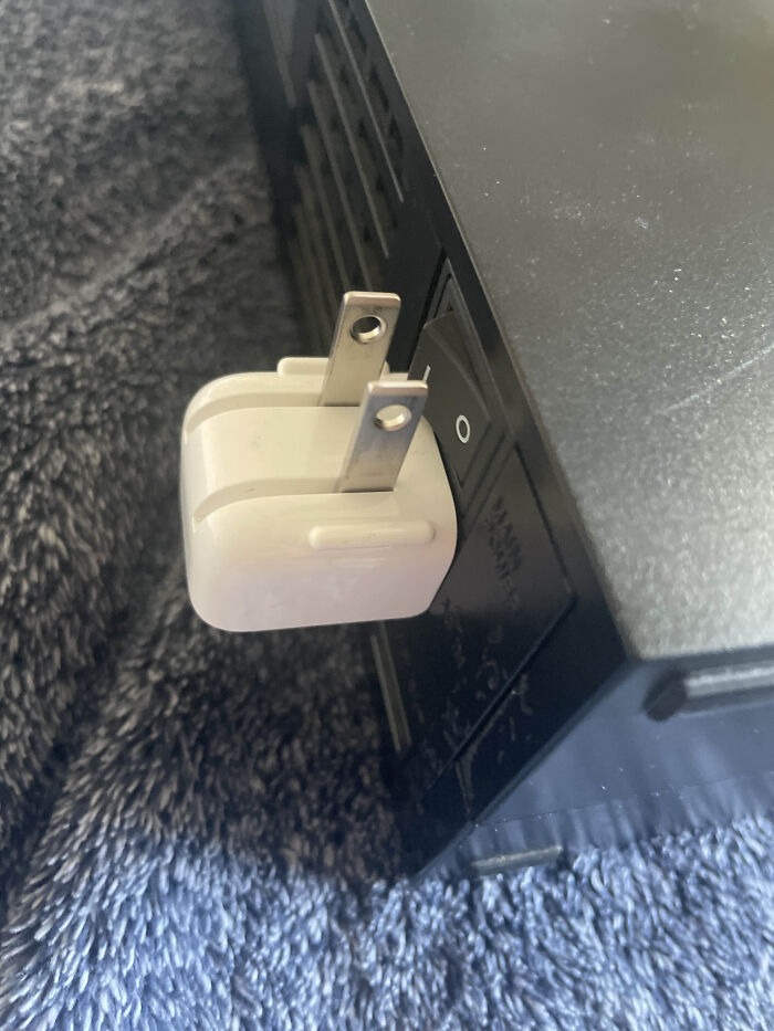 Tech support worker error showing a charger plug incorrectly inserted into a power switch socket on a device.