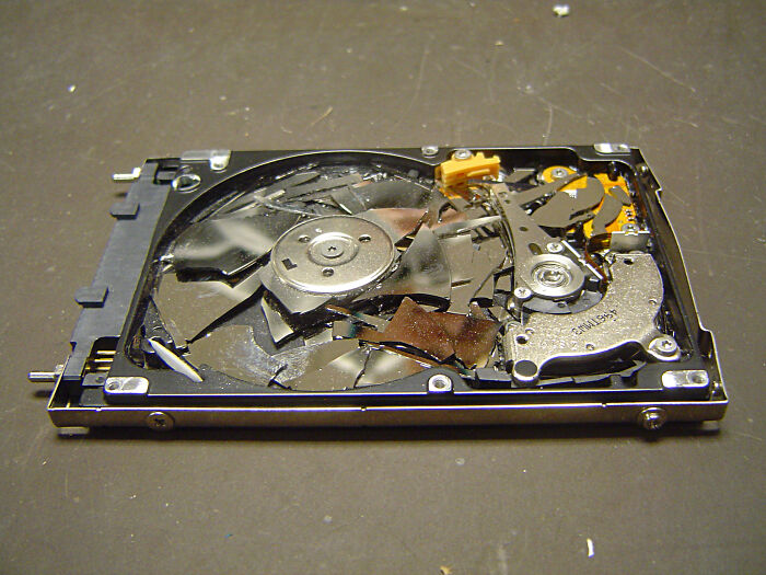 Broken hard drive with shattered platters exposed, illustrating common tech support worker frustrations and challenges.
