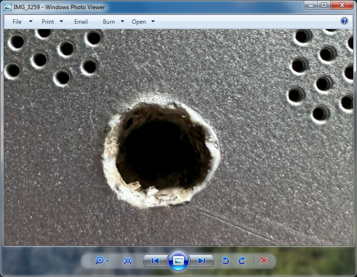 Close-up of damaged computer casing with a large hole, illustrating tech support workers' daily hardware challenges.