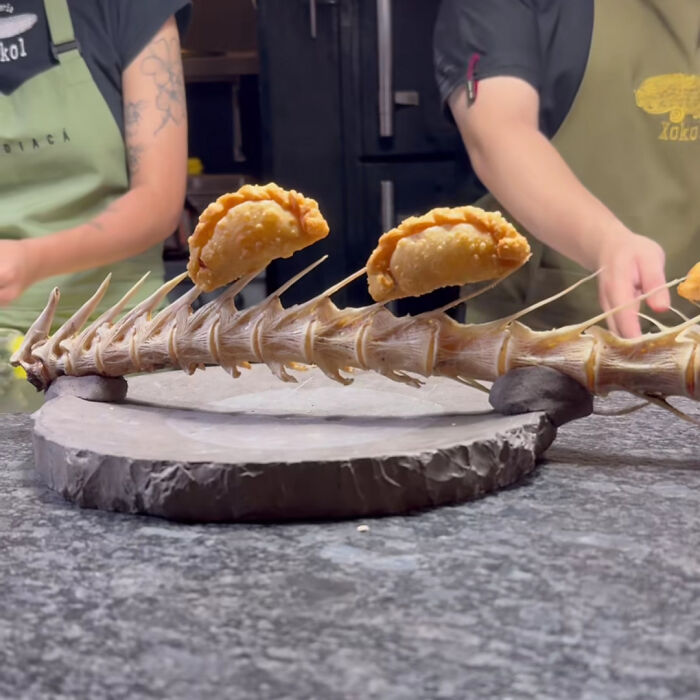 Ridiculous food presentation with fried appetizers skewered on a fish spine served on a stone platter in a restaurant setting
