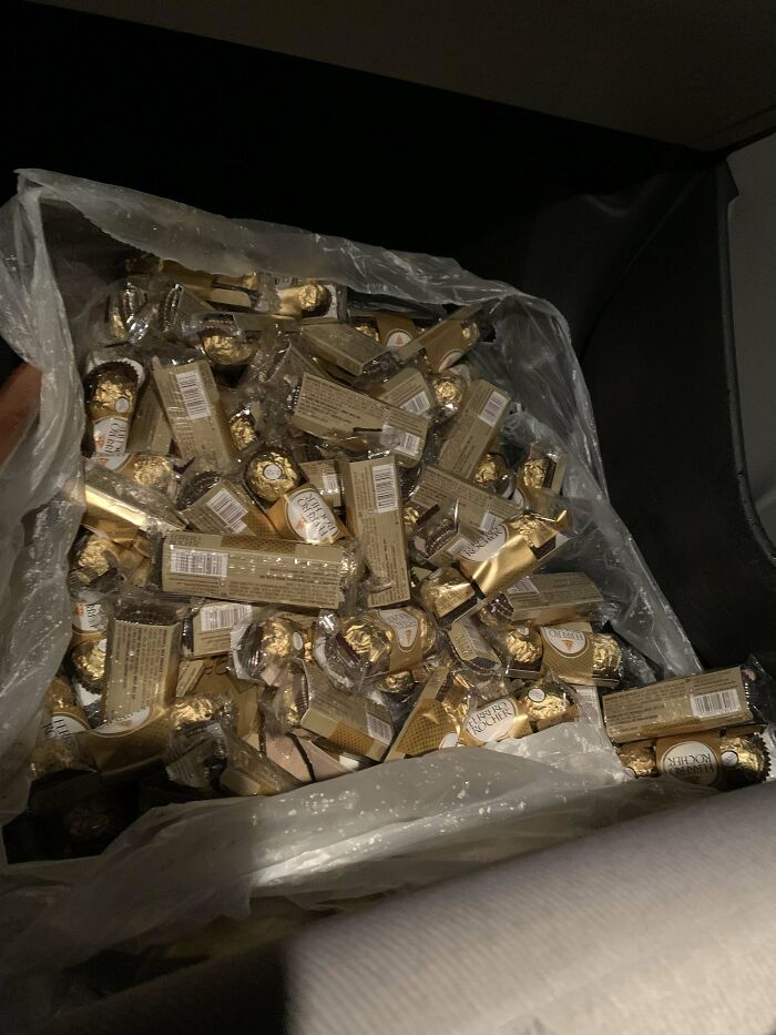 Large pile of Ferrero Rocher chocolates in a plastic bag found as dumpster diving treasures at night.