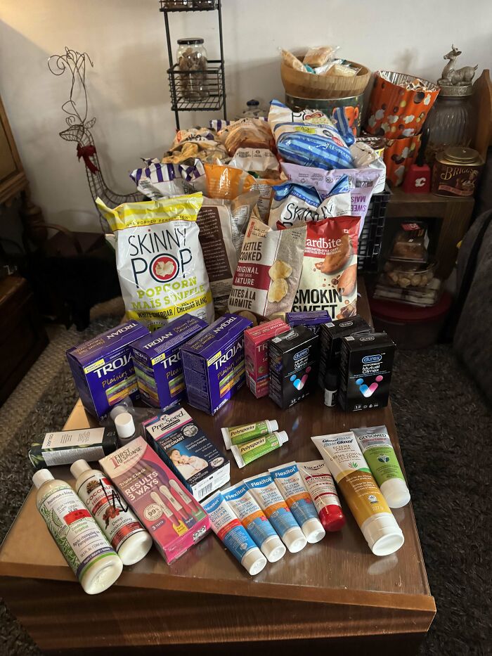Assorted snacks, personal care items, and health products arranged on a table as dumpster diving treasures.