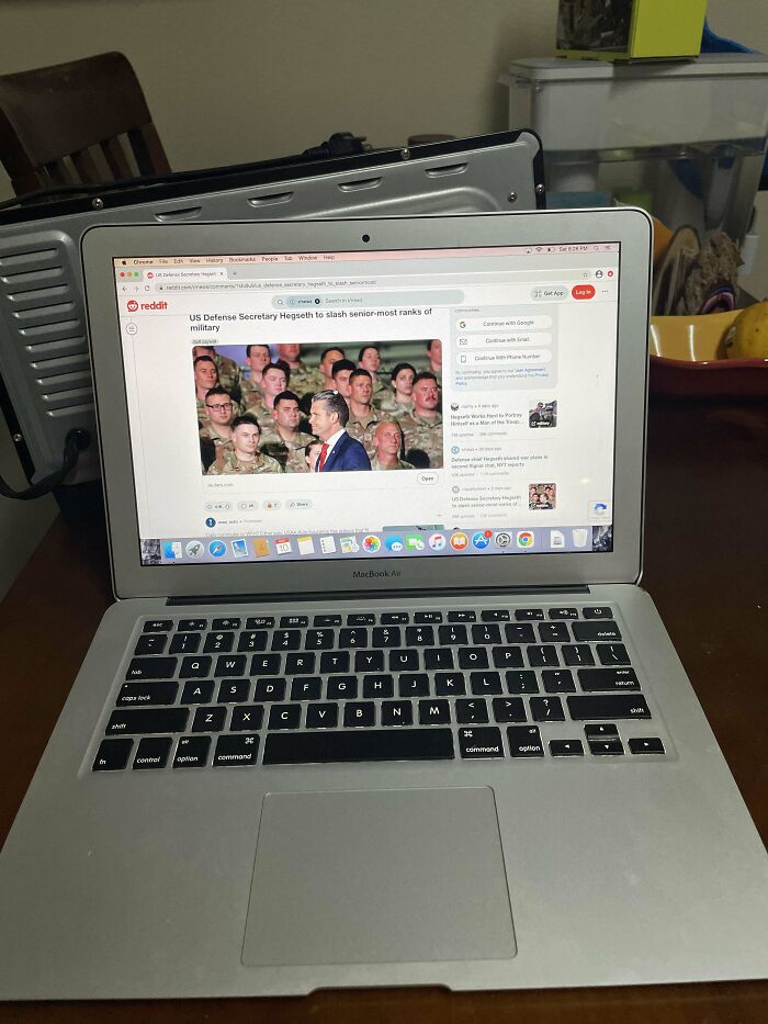 MacBook Air on table displaying Reddit with US Defense Secretary article, highlighting dumpster diving treasures theme.