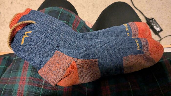 Close-up of blue and orange Darn Tough socks on legs wearing plaid, a popular Buy It For Life purchase.
