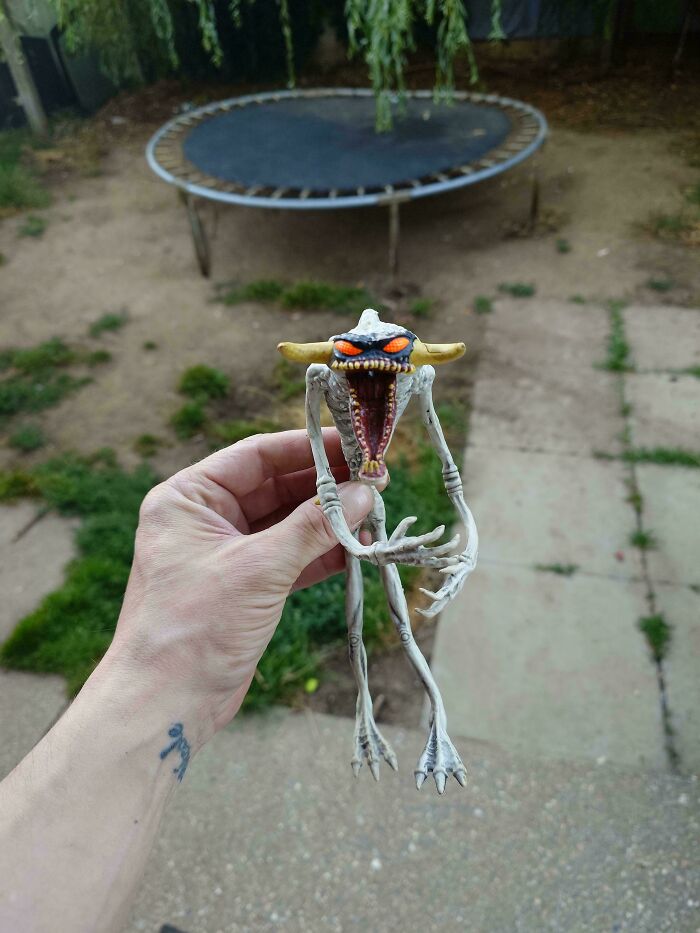 A hand holds a skeletal toy figure with orange eyes and an open, fanged mouth; an example of a Buy It For Life purchase.
