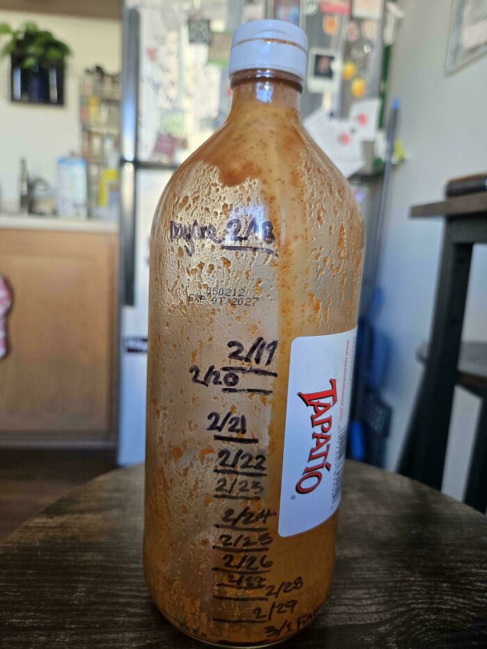 Partially used Tapatío hot sauce bottle with dates marked to track consumption over time, showing moderately interesting usage.