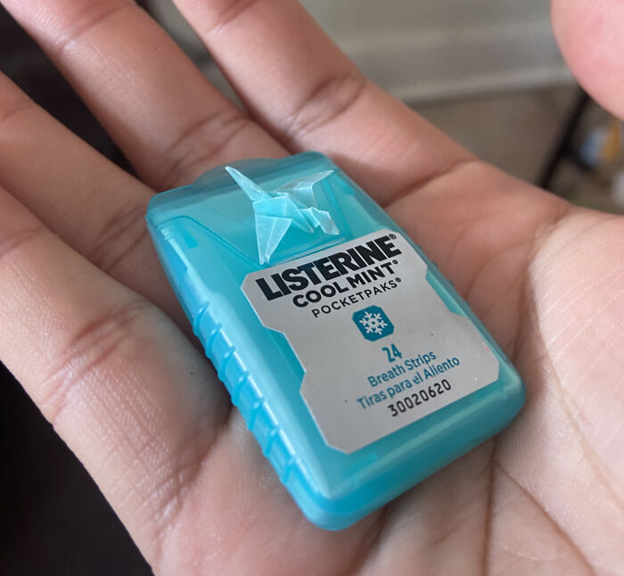 Small Listerine breath strips pack held in hand with a tiny origami crane attached on top, moderately interesting detail.