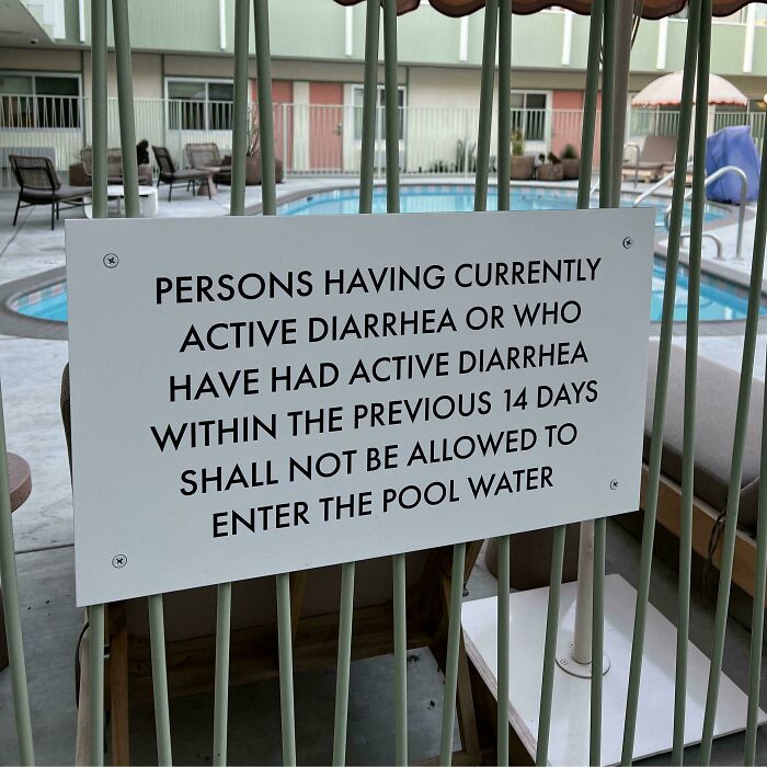 Warning sign by a pool stating people with active or recent diarrhea in the past 14 days cannot enter the pool water.