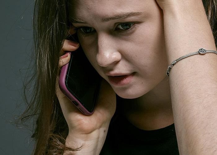 Worried woman on phone showing signs of fear and stress after a red-flag argument in her relationship.