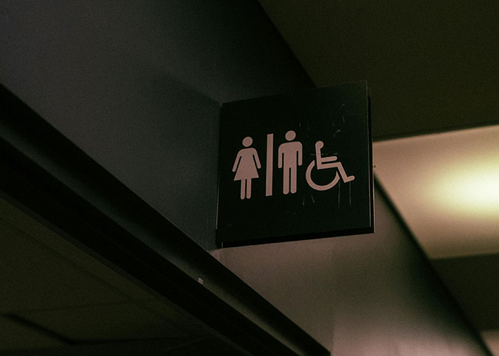 Restroom sign in workplace hallway highlighting accessibility, relating to micromanagement and workplace environment concerns.