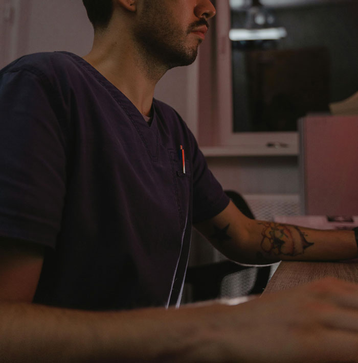 Medical professional working at a desk during nighttime, highlighting concerns about patients’ privacy in healthcare settings. - 21