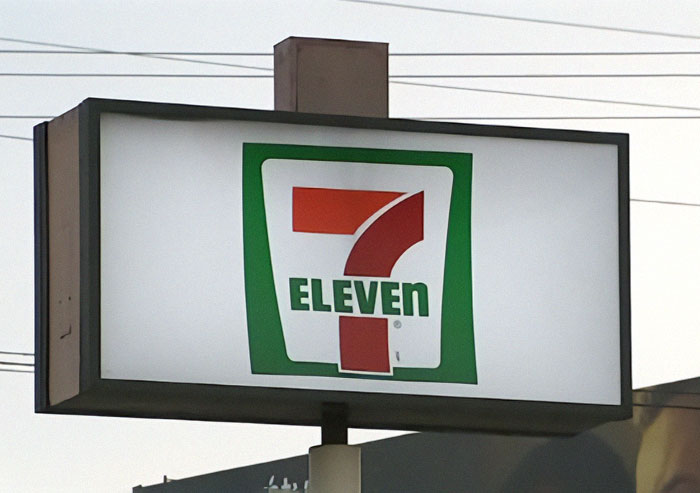 7-Eleven store sign outdoors with power lines in the background, related to worker passes away after manager incident.