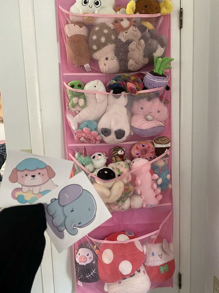 Pink hanging mesh organizer on a door holding various stuffed toys, demonstrating clever products to organize chaotic corners.