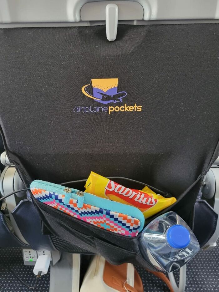 Airplane pockets organizer attached to a seatback holding snacks, a colorful pouch, and a water bottle for travel convenience.