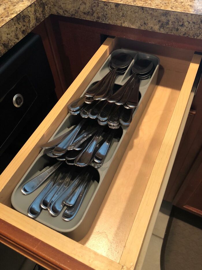 Drawer organizer holding neatly arranged silverware in a kitchen drawer, showcasing clever products to organize home corners.