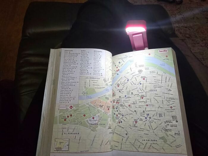 Open travel guide map of Sevilla on a chair illuminated by a small red LED light showing under-the-radar finds.