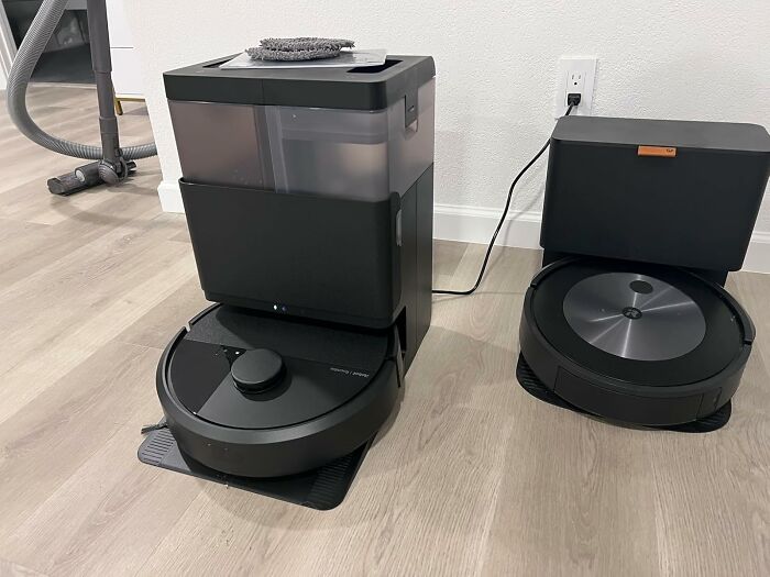Two smart robot vacuum cleaners on charging docks on a light wood floor, showcasing Prime Day electronic deals.
