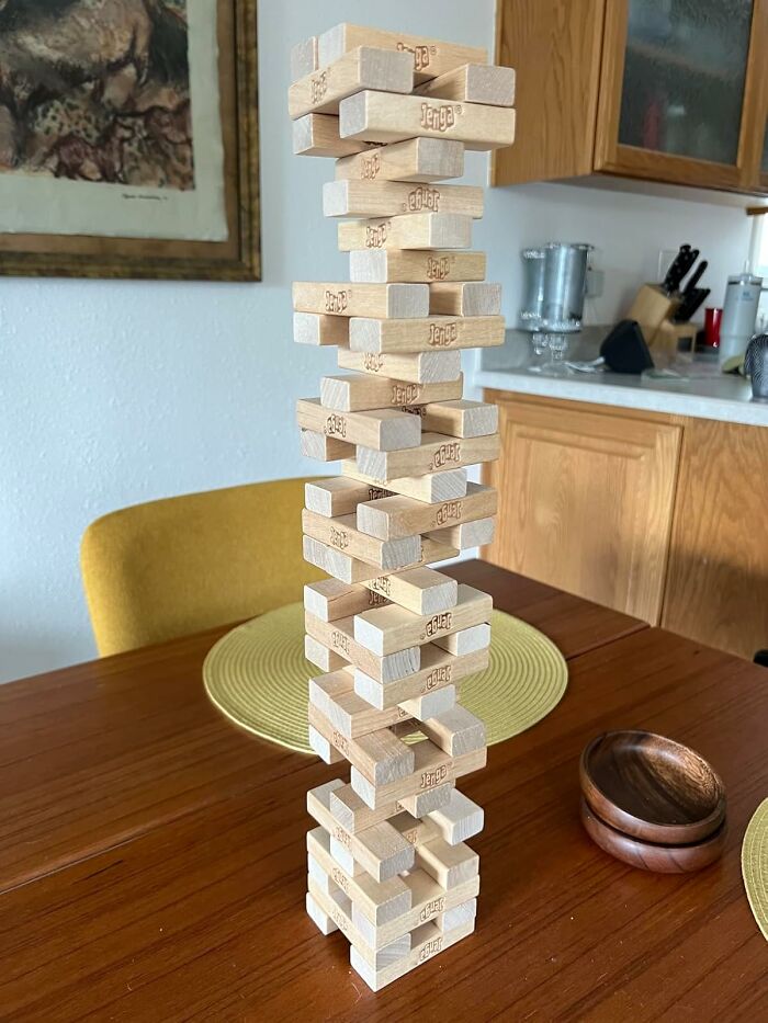 Stacked wooden Jenga toy blocks on a dining table, a creative and affordable toy under $20 for gifting.