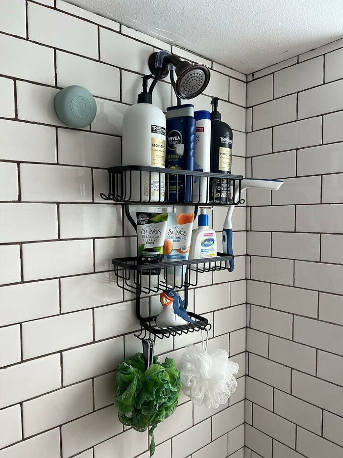 Black metal shower caddy with multiple shelves organizing toiletries and bath accessories in a tiled shower corner.