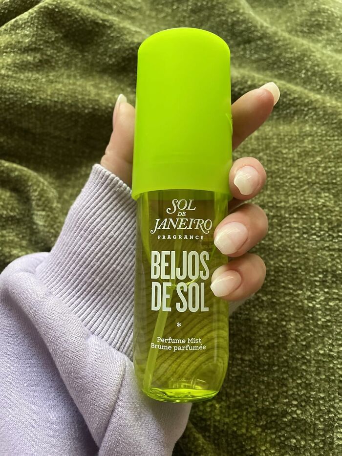 Hand holding Sol de Janeiro Beijos de Sol perfume mist, one of the most-wished-for Amazon finds in green bottle.