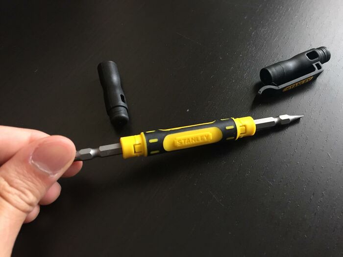 Hand holding a Stanley multitool screwdriver on a black surface, showcasing an under-the-radar useful find.