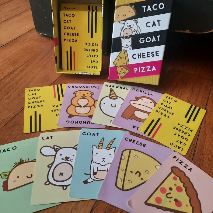 Colorful taco cat goat cheese pizza card game laid out on wooden floor, a fun toy under $20 for gifting genius.