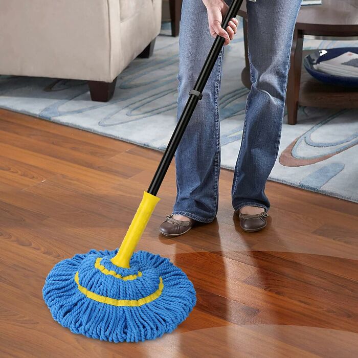 Person using a blue and yellow mop to clean hardwood floor demonstrating popular infomercial cleaning tool.