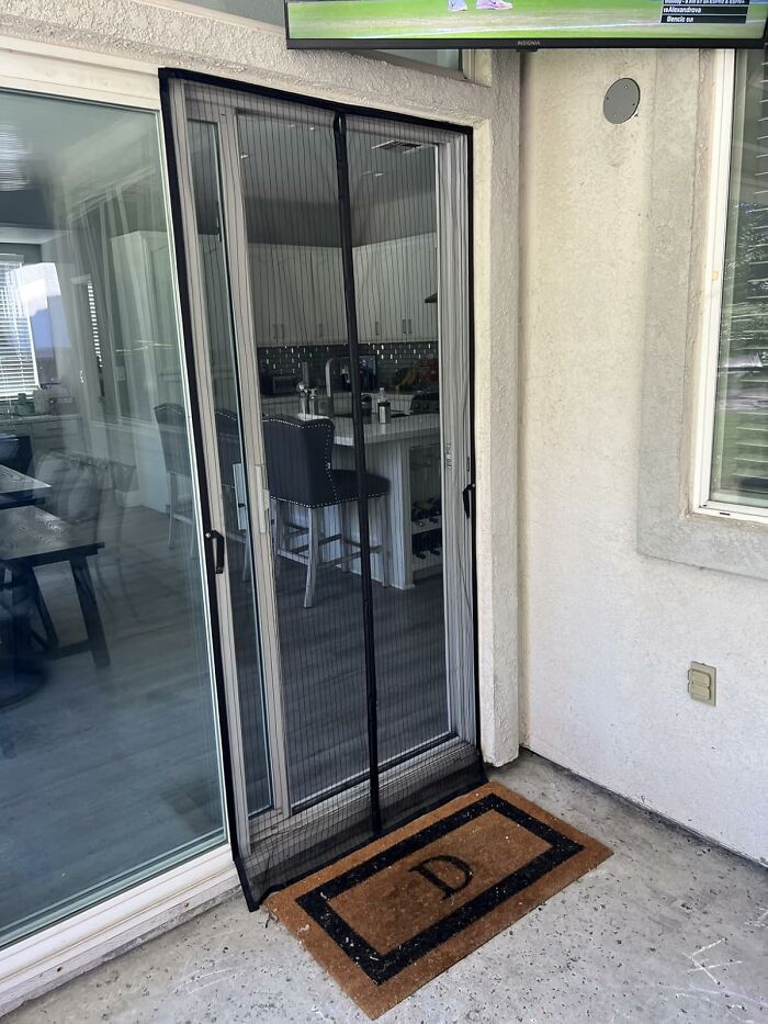 Magnetic screen door installed on a glass sliding door with a doormat, one of the most wished for items on Amazon this week.