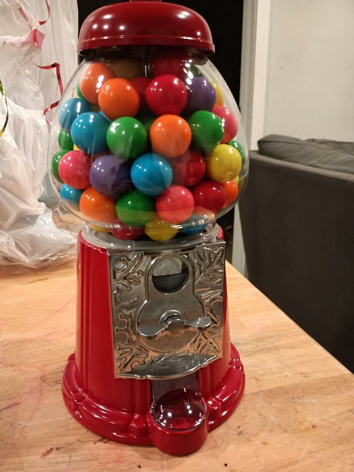 Retro gumball machine filled with colorful gumballs on a wooden table, a classic nostalgic vintage find for old souls.