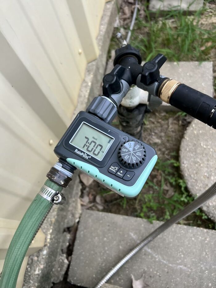 Outdoor irrigation timer attached to garden hose and faucet, helping manage water during heatwave conditions.