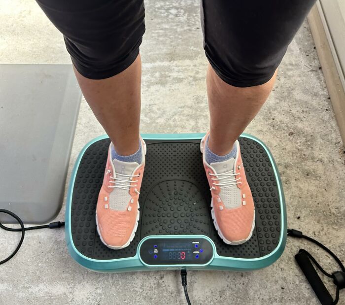 Person wearing pink sneakers standing on a vibration plate machine, one of the best sellers that topped the charts this Prime Day.