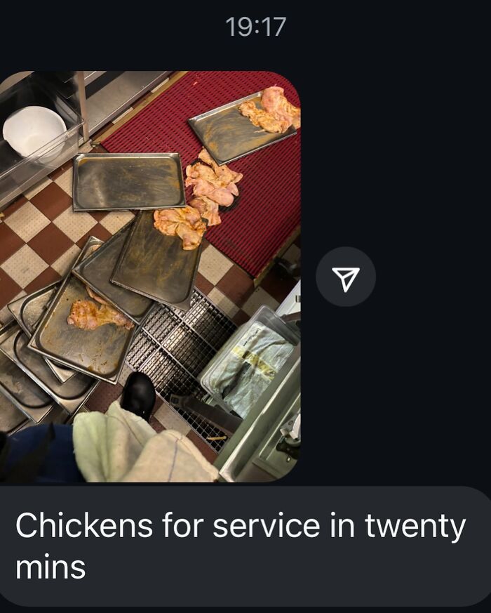 Overhead view of kitchen floor with multiple baking trays and raw chicken pieces scattered, showcasing relatable chef humor.