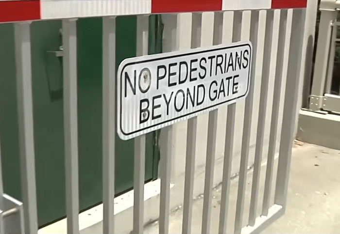No pedestrians beyond gate sign on metal railing at rising drawbridge warning people not to cross. No pedestrians beyond gate sign on metal railing at rising drawbridge warning people not to cross.