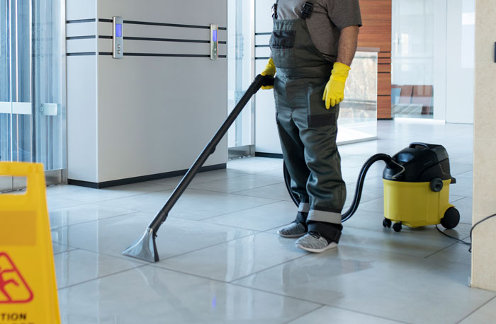 Personal de limpieza en hospital usando aspiradora profesional para mantenimiento de pisos en áreas hospitalarias importantes.