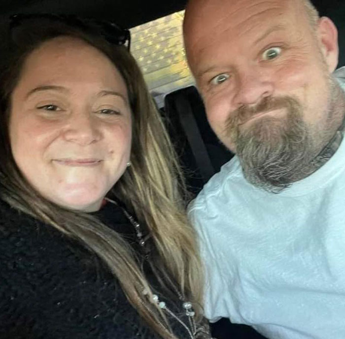 Couple sitting in a car, smiling at the camera, related to a tragic story involving a girl who found parents' bodies.