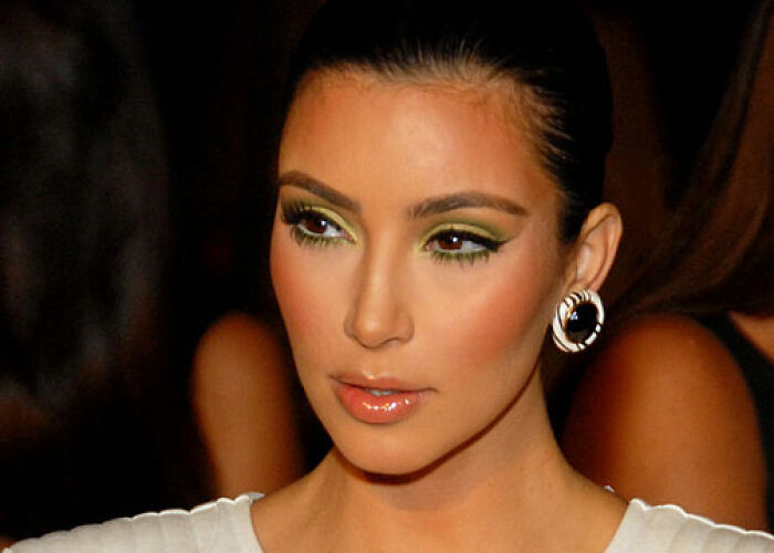 Close-up of a KarJenner clan member wearing green eye makeup and stylish earrings at a social event. - 17