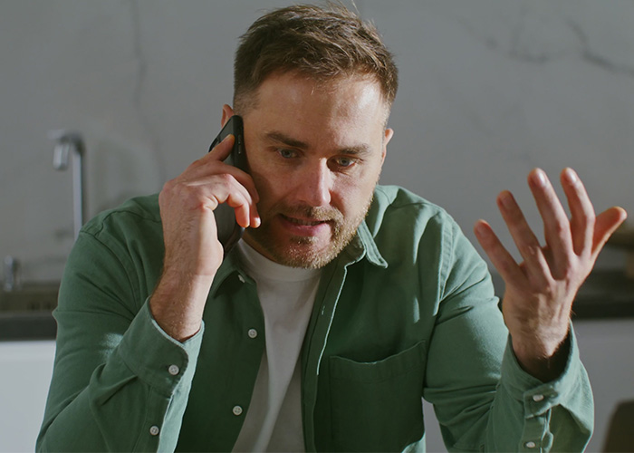 Man in green shirt on phone looking frustrated, illustrating former employees revealing crazy secrets at work. - 13