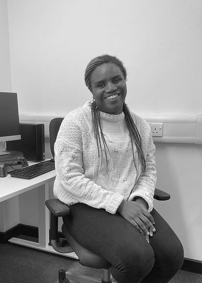 Beyonc&eacute; fan sitting in office chair, smiling calmly after a dehumanizing experience at Cowboy Carter concert.